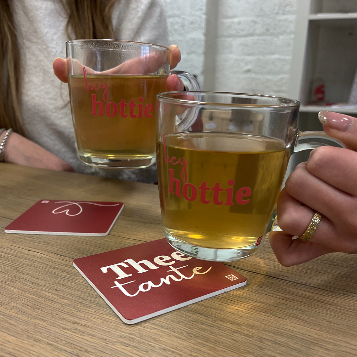 twee mensen die thee drinken uit theeglazen met opdruk hey hottie